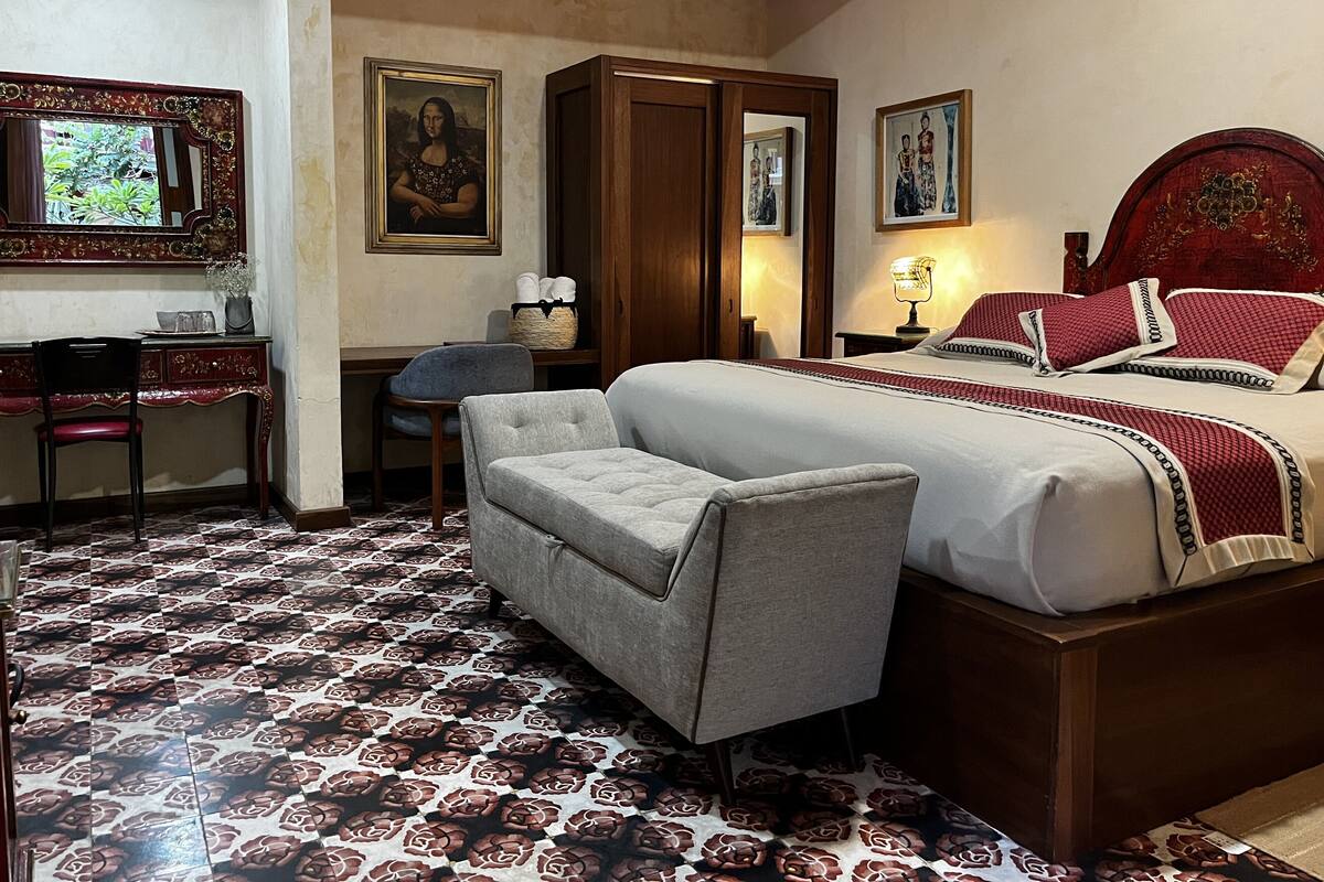 Ein Schlafzimmer mit Bett, Schreibtisch, Stuhl, Kleiderschrank und einem gemusterten Boden.