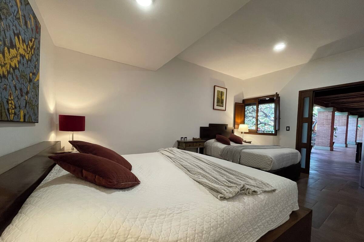 Ein Hotelzimmer mit zwei Betten, einem großen Gemälde an der Wand und einem Fenster mit Blick.