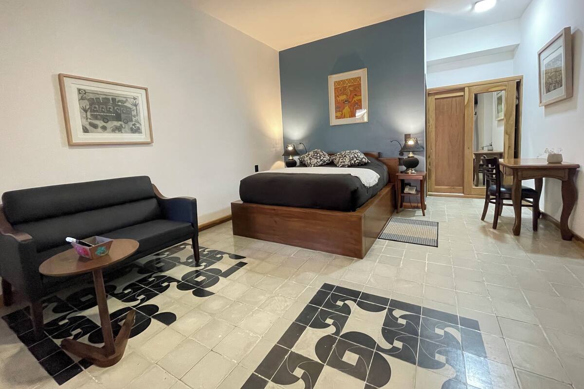 Ein Hotelzimmer mit Bett, Sofa, kleinem Tisch und Schreibtisch.