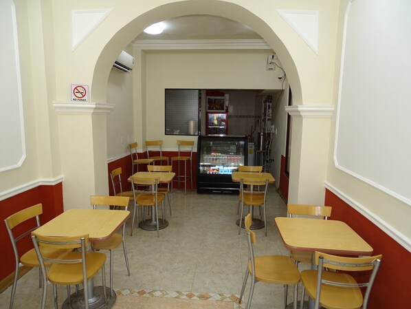 A restaurant interior with tables and chairs, a refrigerator, and a 'No Smoking' sign.
