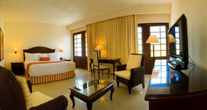 Una habitación de hotel con cama, escritorio, silla, televisor y lámpara.