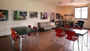 Un comedor con sillas rojas, una mesa negra y un sofá. Varias imágenes enmarcadas decoran las paredes.
