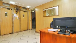 A hotel lobby with wooden doors, a reception desk, a computer, and a mirror on the wall. - MZapartments Bulhoes (Rio de Janeiro)