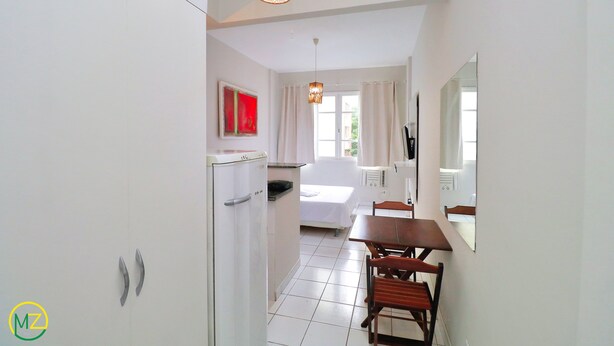 A hotel room with a bed, a small kitchenette, a dining area with a table and chairs, and a large mirror. - MZapartments Bulhoes (Rio de Janeiro)