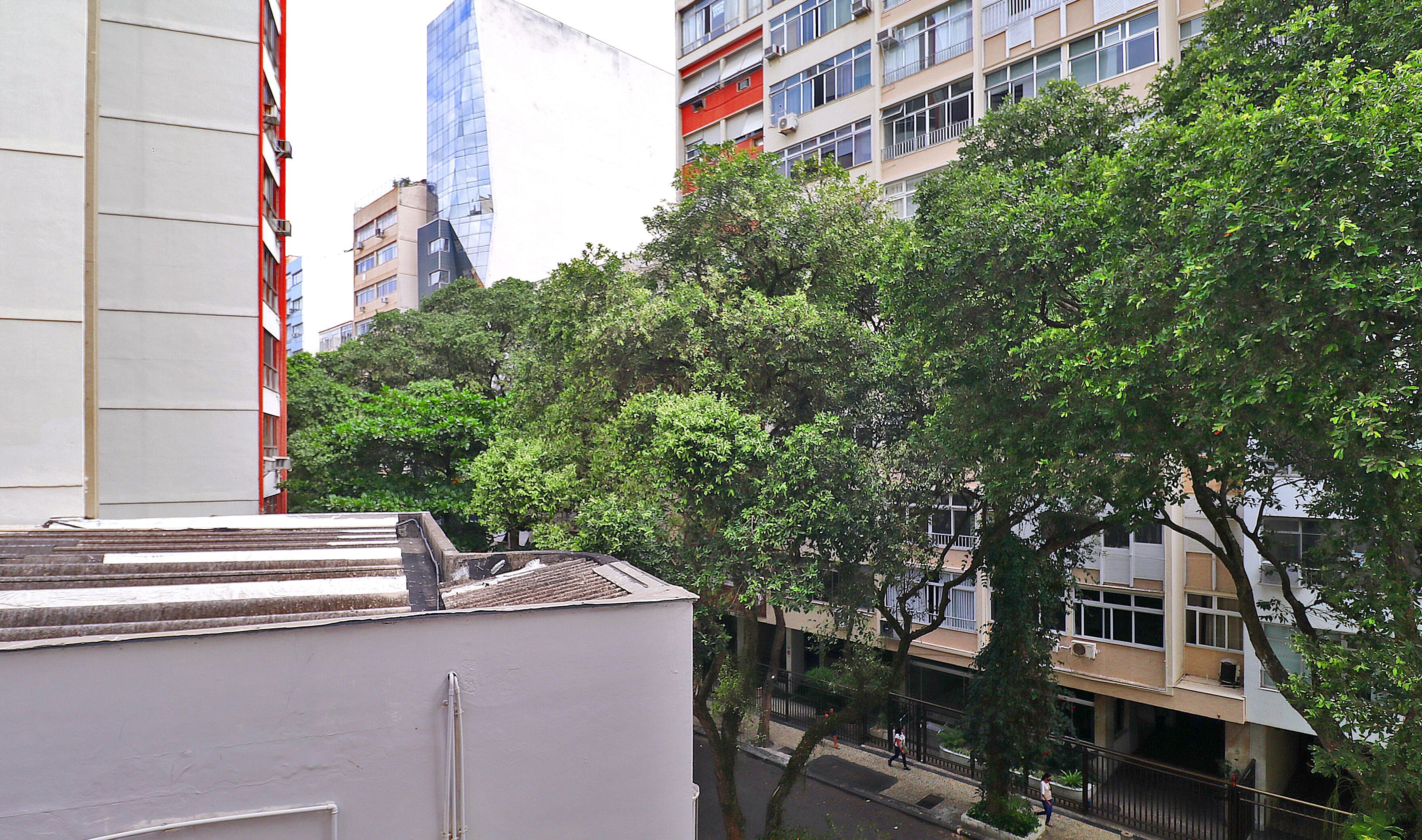 Un paysage urbain avec des bâtiments modernes, une rue bordée d’arbres et un ciel dégagé.