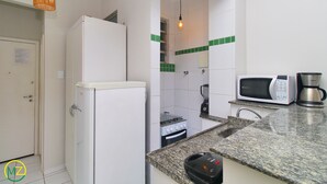 A compact kitchen with a refrigerator, microwave, coffee maker, and a small stove. - MZapartments Bulhoes (Rio de Janeiro)