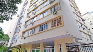 A multi-story building with balconies, a gated entrance, and a sign indicating a residential area. - MZapartments Bulhoes (Rio de Janeiro)