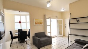 A living room with a sofa, chairs, a TV, a ceiling fan, and a dining area with a table and chairs. - MZapartments Djalma (Rio de Janeiro)