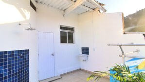 A bathroom with a shower, a window, a sink, and a tiled wall. - MZapartments Djalma (Rio de Janeiro)