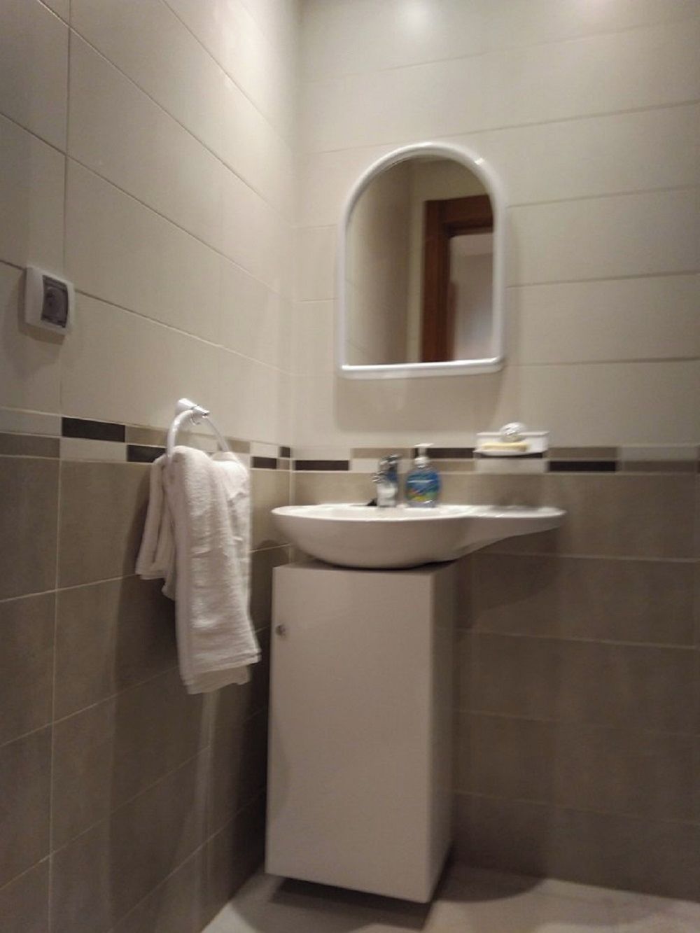 A bathroom with a white sink, a mirror, and a towel rack.