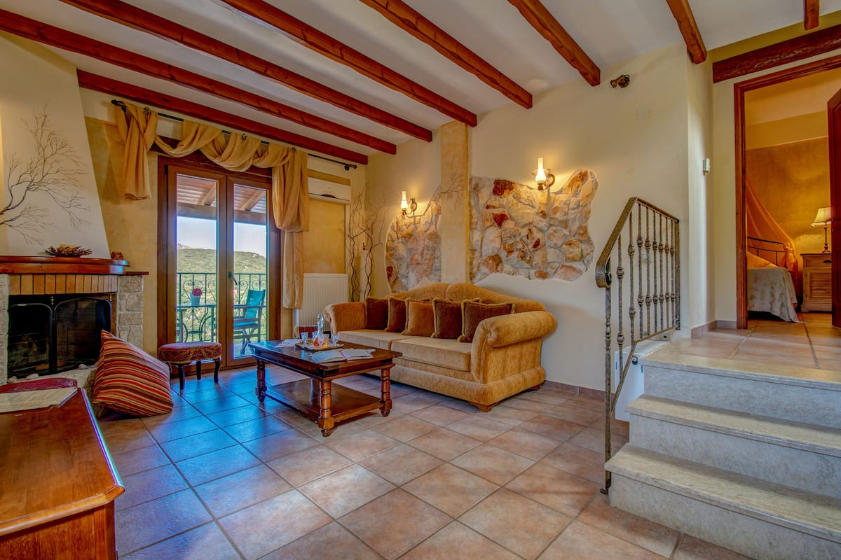 Una sala de estar acogedora con chimenea, un sofá, una mesa de centro y una escalera que sube a otro nivel.