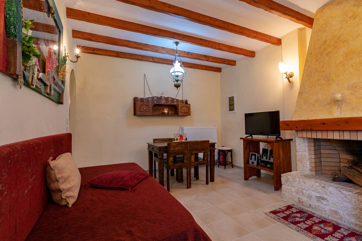 Una sala de estar acogedora con un sofá rojo, una mesa de comedor de madera y una chimenea.