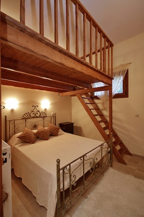 A bedroom with a wooden bunk bed, a single bed with a headboard, a nightstand, and a staircase leading to an upper level. - Sokraki Villas (Corfu)