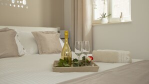 A neatly made bed with a tray containing a bottle and two glasses, a window with plants, and a wall with circular cut-outs. - Villa Daky (Split)