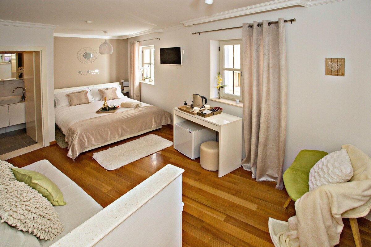 Une chambre comprenant un lit, un bureau, une chaise et un petit coin cuisine.