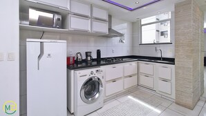 Una cocina moderna con armarios blancos, lavadora integrada, microondas y cocina a gas.