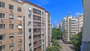 Un edificio residencial de varios pisos con balcones, aire acondicionado y un cielo azul despejado.