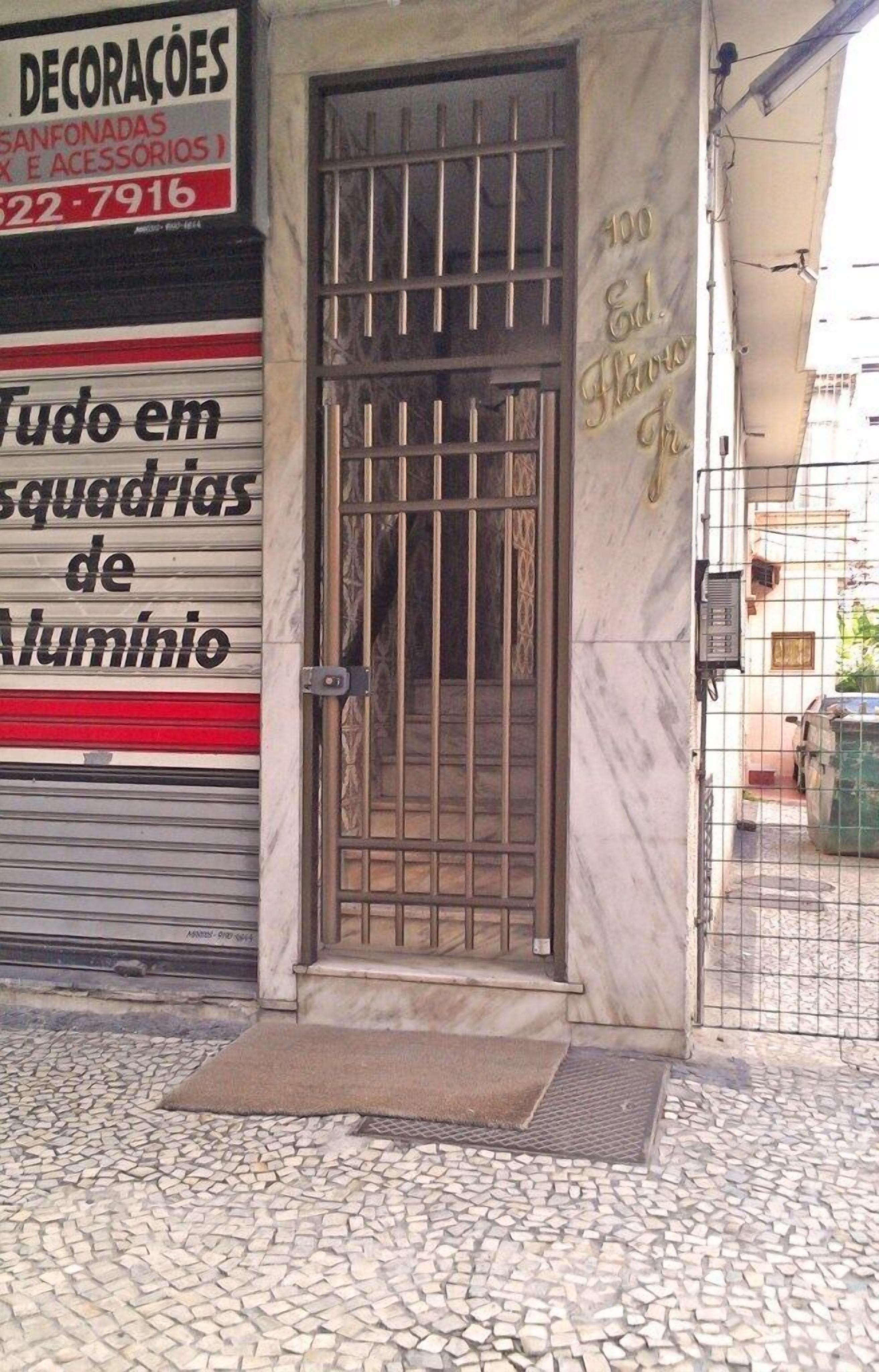 A storefront with a metal gate and a sign advertising aluminum window frames.
