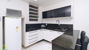 A compact kitchen with white cabinets, a microwave, a toaster, and a black countertop. - MZapartments Prado II (Rio de Janeiro)