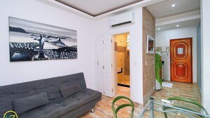 Een moderne woonkamer met een grijze bank, een groot abstract schilderij en een houten vloer.