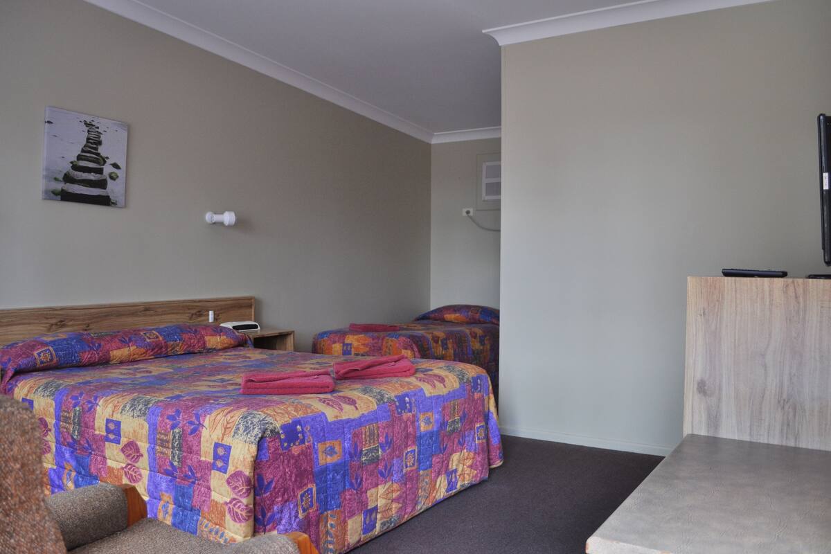 Een hotelkamer met twee bedden, een houten hoofdbord, een bureau en een stoel.