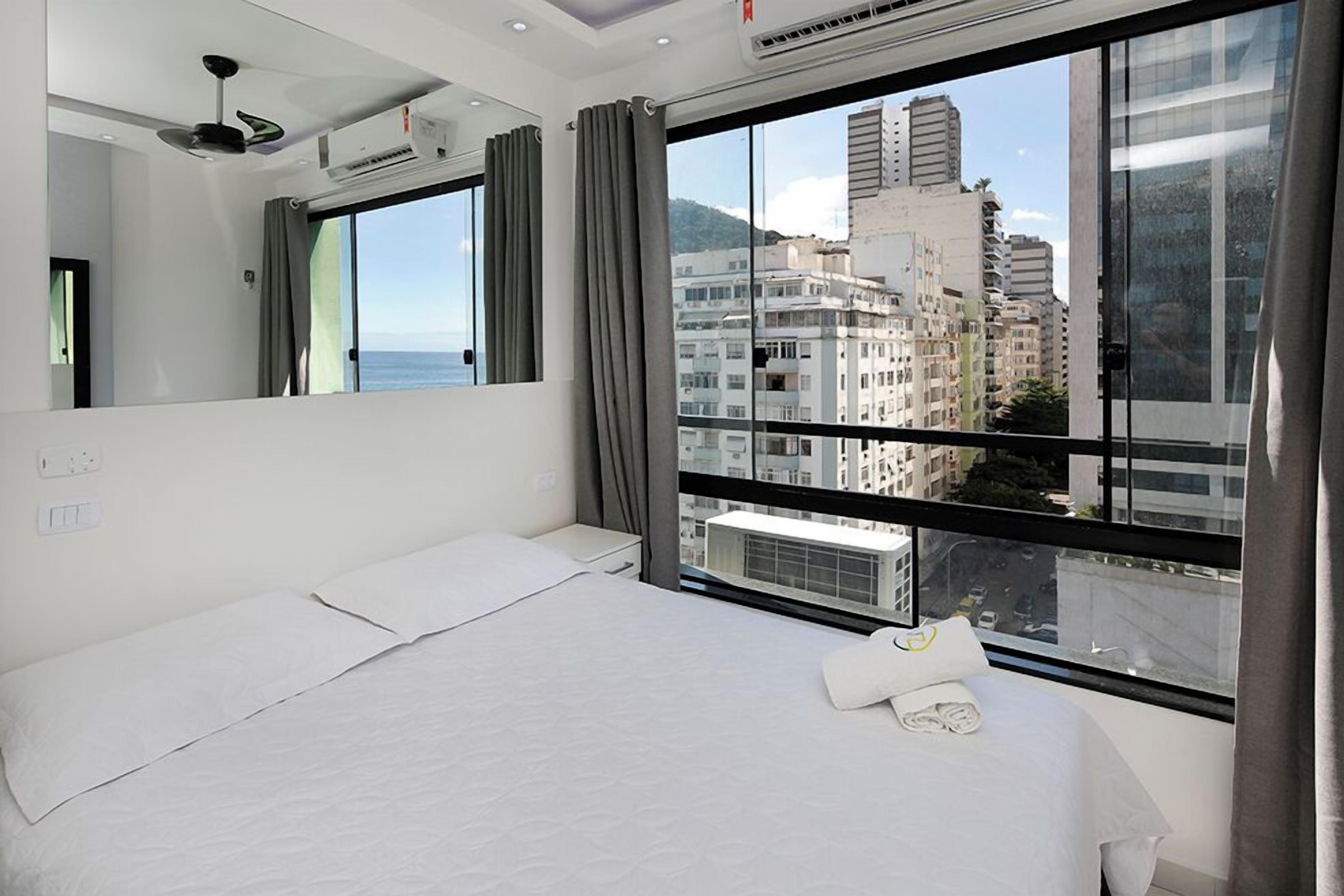 Habitación de hotel moderna con una cama grande, vistas de la ciudad y un balcón.