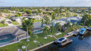 Un quartier résidentiel avec des maisons, une piscine et un quai où sont amarrés des bateaux.