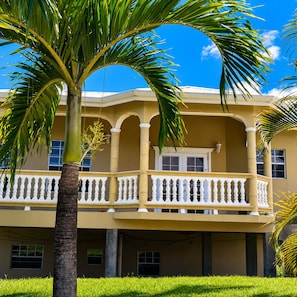 A building with a balcony, columns, and a clear blue sky.