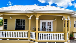 A yellow building with a white balcony, a door with a sign, and windows.