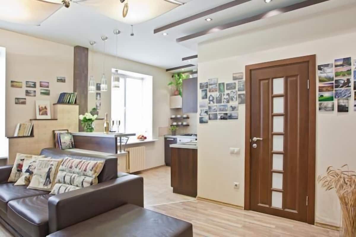 Ein modernes Wohnzimmer mit einer Couch, einem Essbereich mit Tisch und einer Küche im Hintergrund.