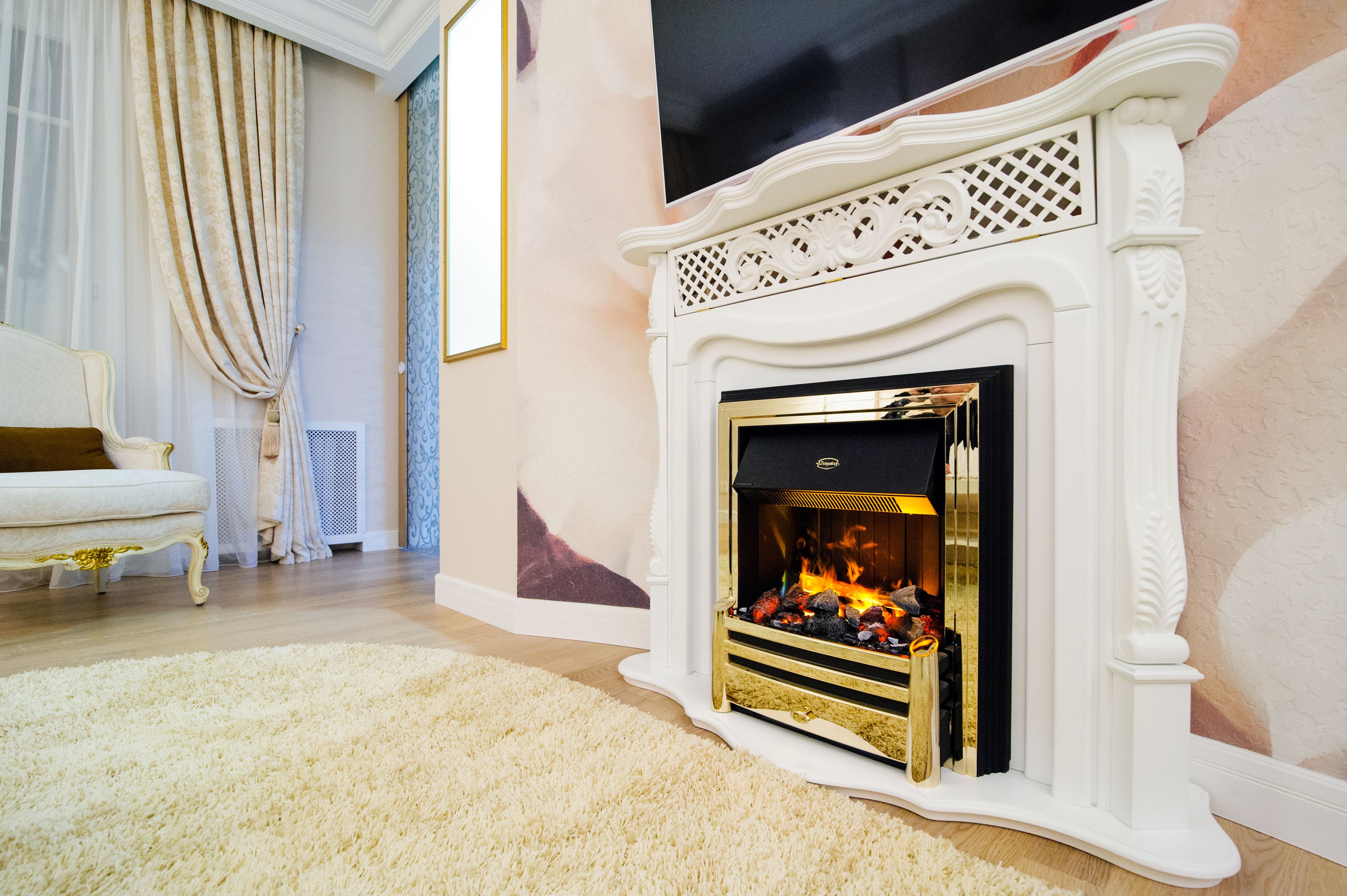 A room with a white fireplace, a white sofa, and a large window with sheer curtains.