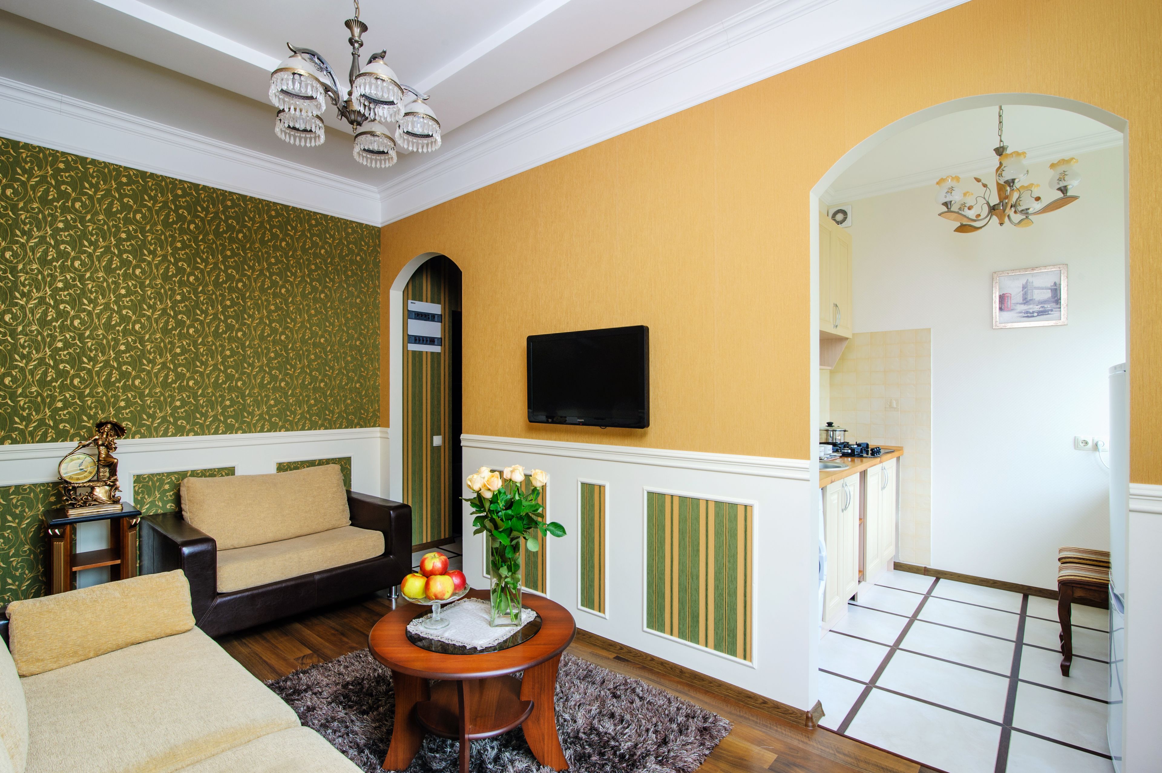 Un salón con un sofá, una mesa baja con fruta y un televisor montado en la pared.
