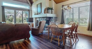 A living room with a fireplace, a dining table with chairs, a sofa, and a television. - Snowcreek Resort Vacation Rental 554 (Mammoth Lakes)