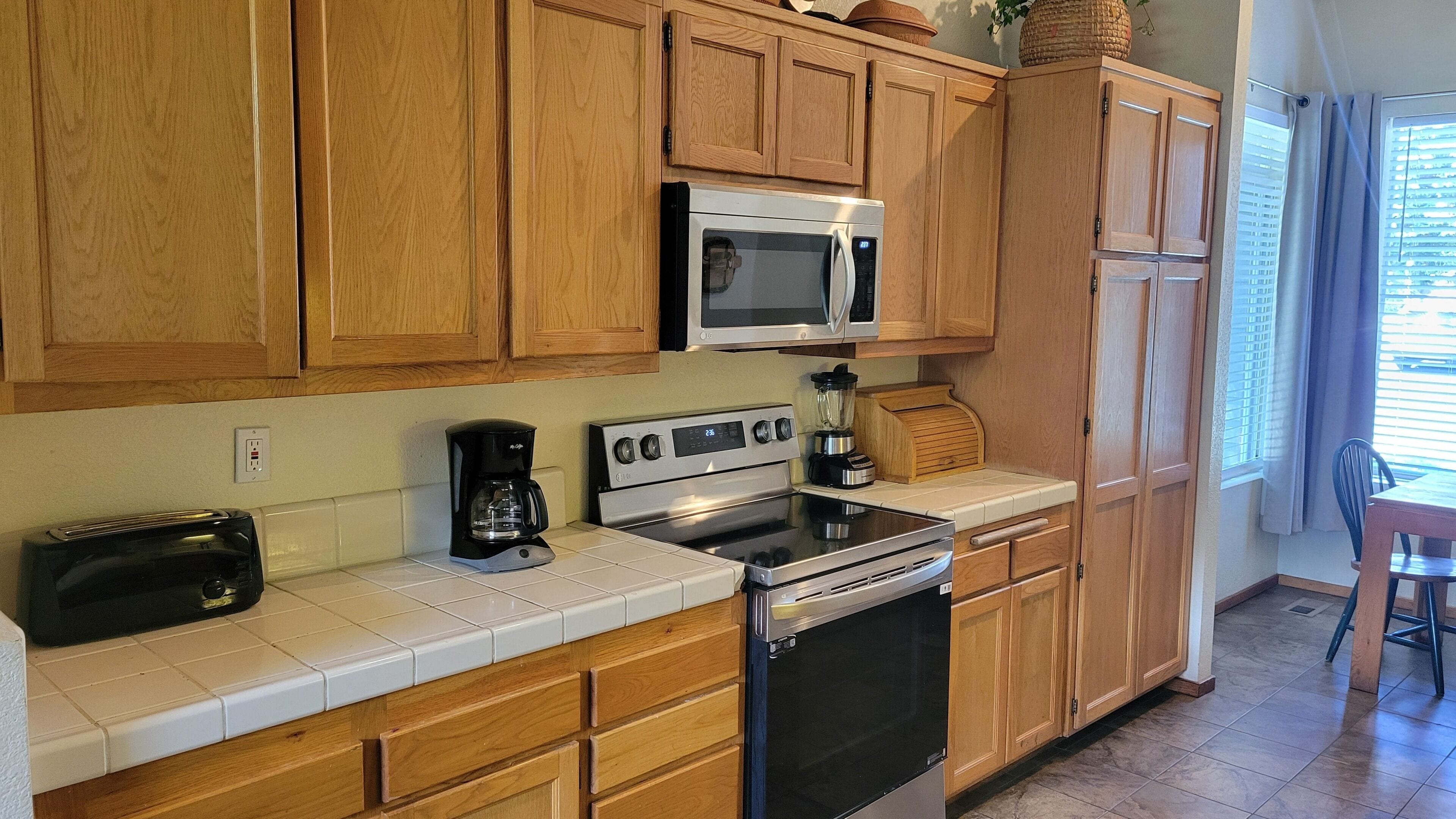 A kitchen with wooden cabinets, a microwave, a coffee maker, and a toaster.