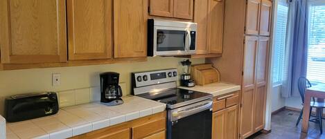 A kitchen with wooden cabinets, a microwave, a coffee maker, and a toaster.