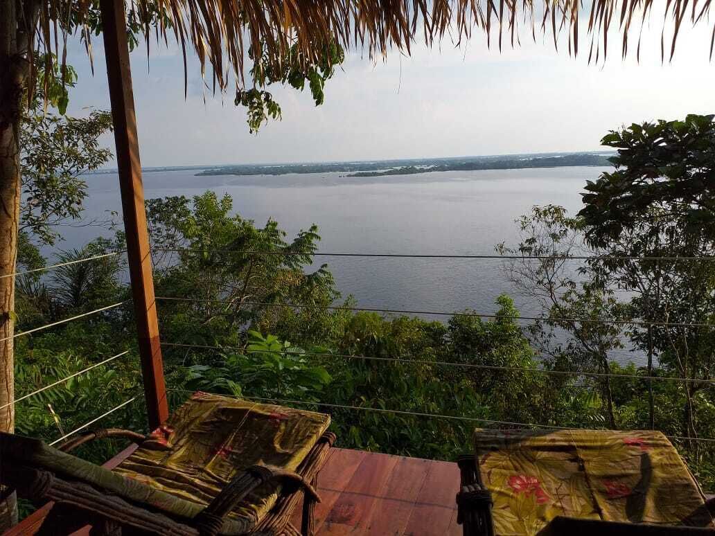 A view from a covered outdoor area overlooking a body of water, with a table and chairs in the foreground.