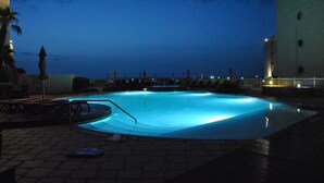 A swimming pool with a view of the city skyline at dusk. - Beachfront and Gorgeous Sunrise Views - A Beach Lover's Paradise  (South Padre Island)