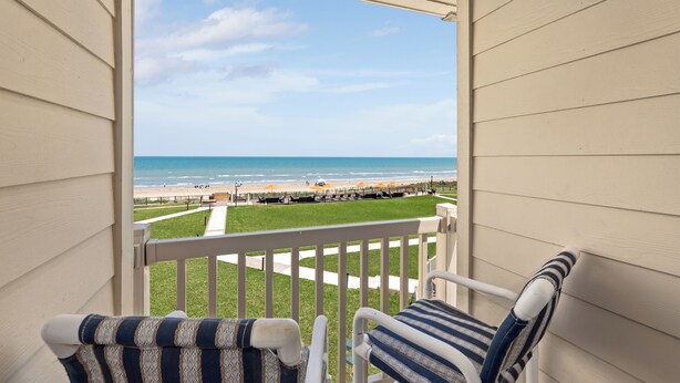 A balcony with a view of the beach, a grassy area, and a pathway leading to the beach. - Beachfront and Gorgeous Sunrise Views - A Beach Lover's Paradise  (South Padre Island)
