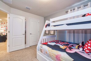 A bunk bed with a Mickey Mouse themed bedspread, white walls, and a door with a handle.