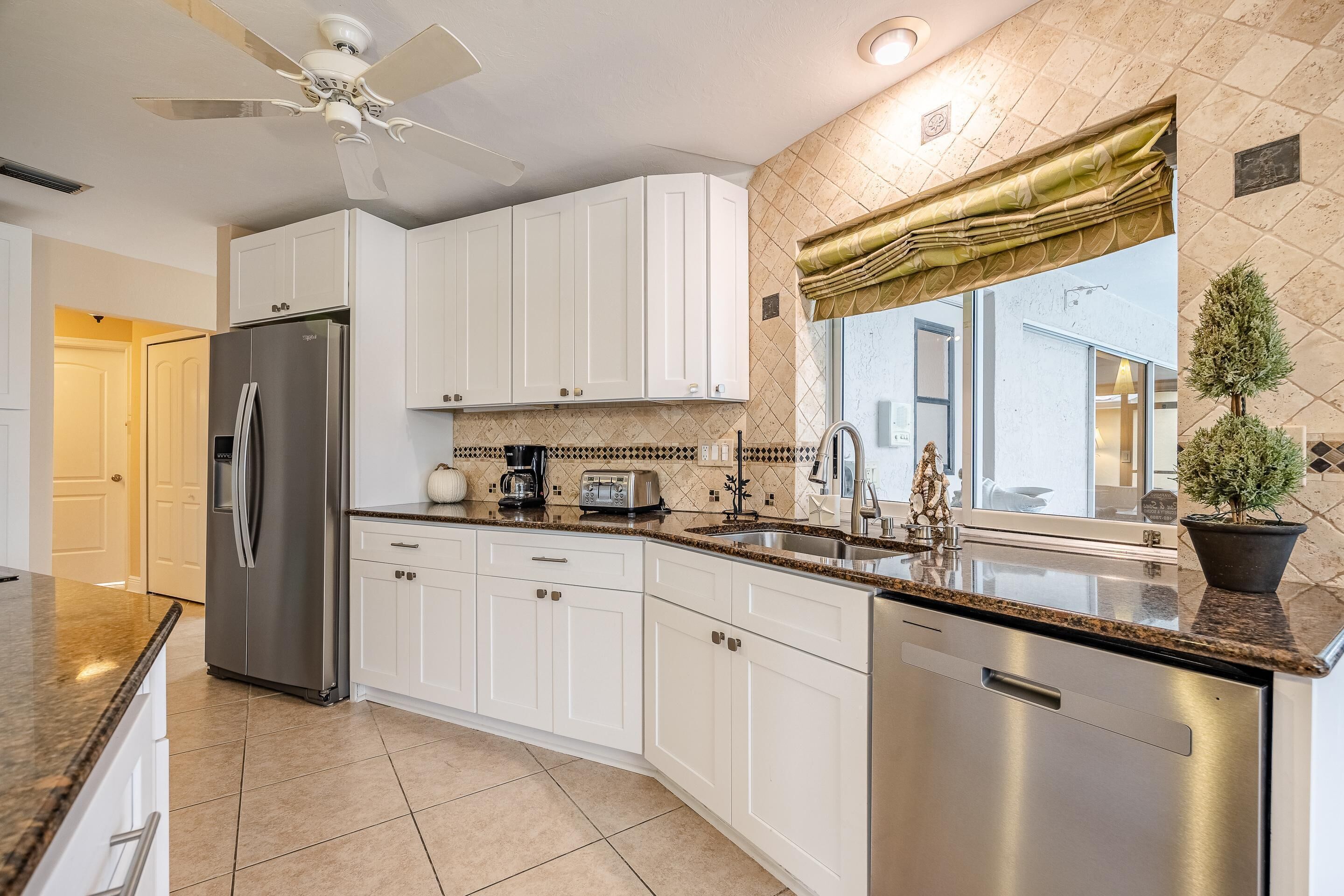 A modern kitchen with white cabinets, stainless steel appliances, and a granite countertop.