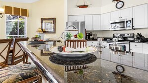 Una cocina moderna con armarios blancos, electrodomésticos de acero inoxidable y una isla central con un pastel.