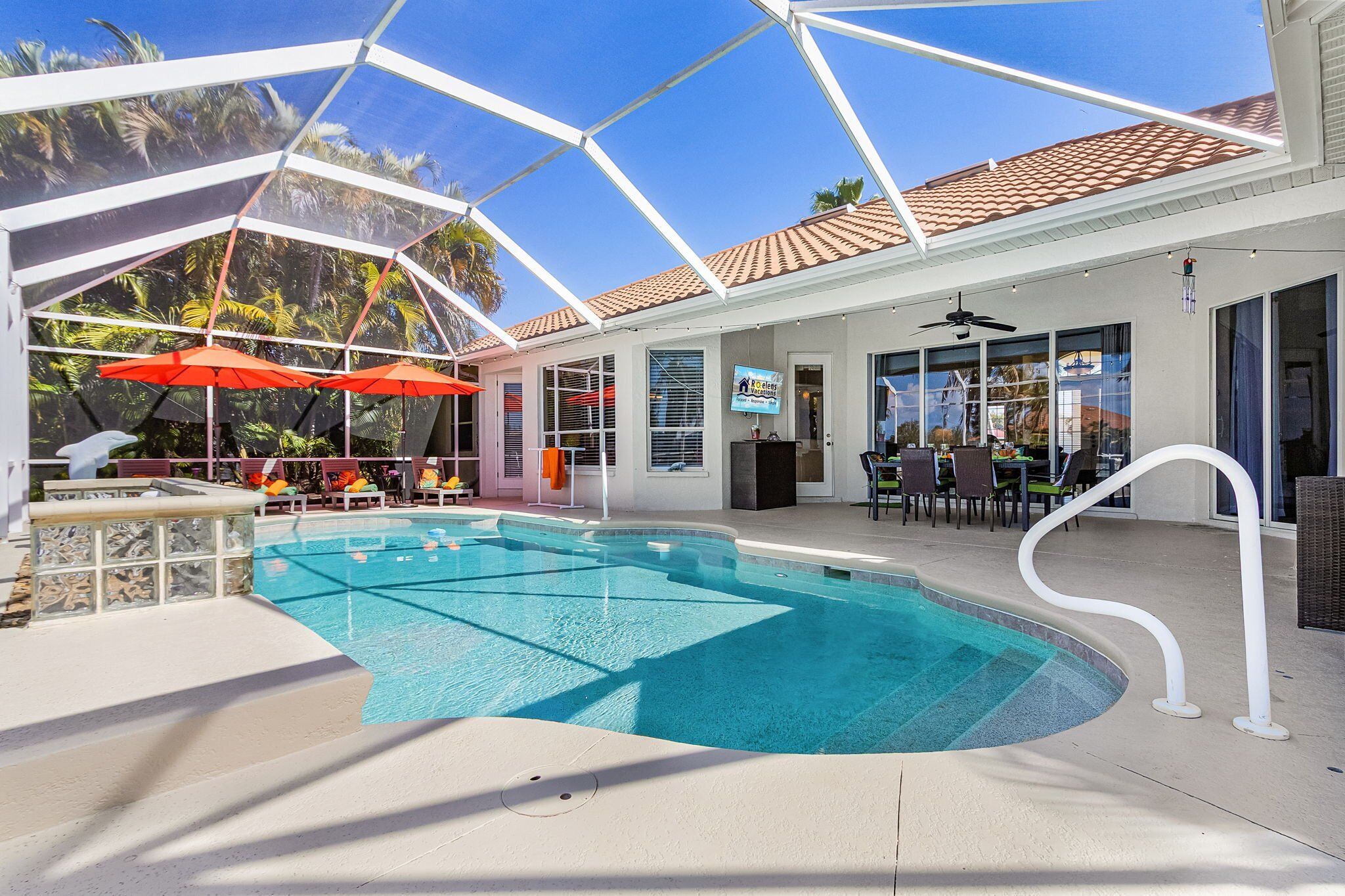 A pool area with a clear blue pool, umbrellas, and lounge chairs.