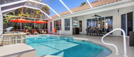A pool area with a clear blue pool, umbrellas, and lounge chairs.