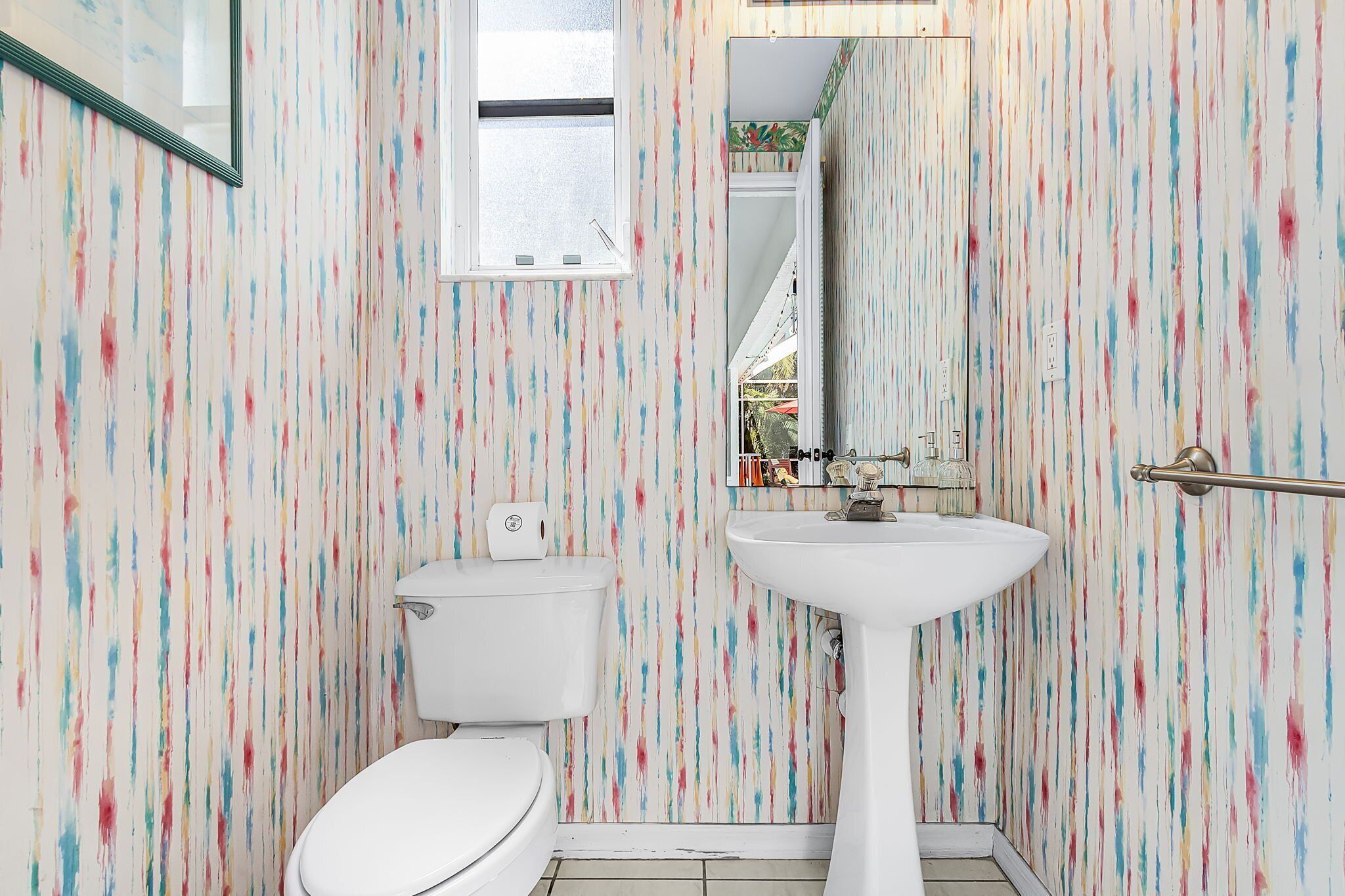 Ein Badezimmer mit Toilette, Waschbecken und einem Fenster.