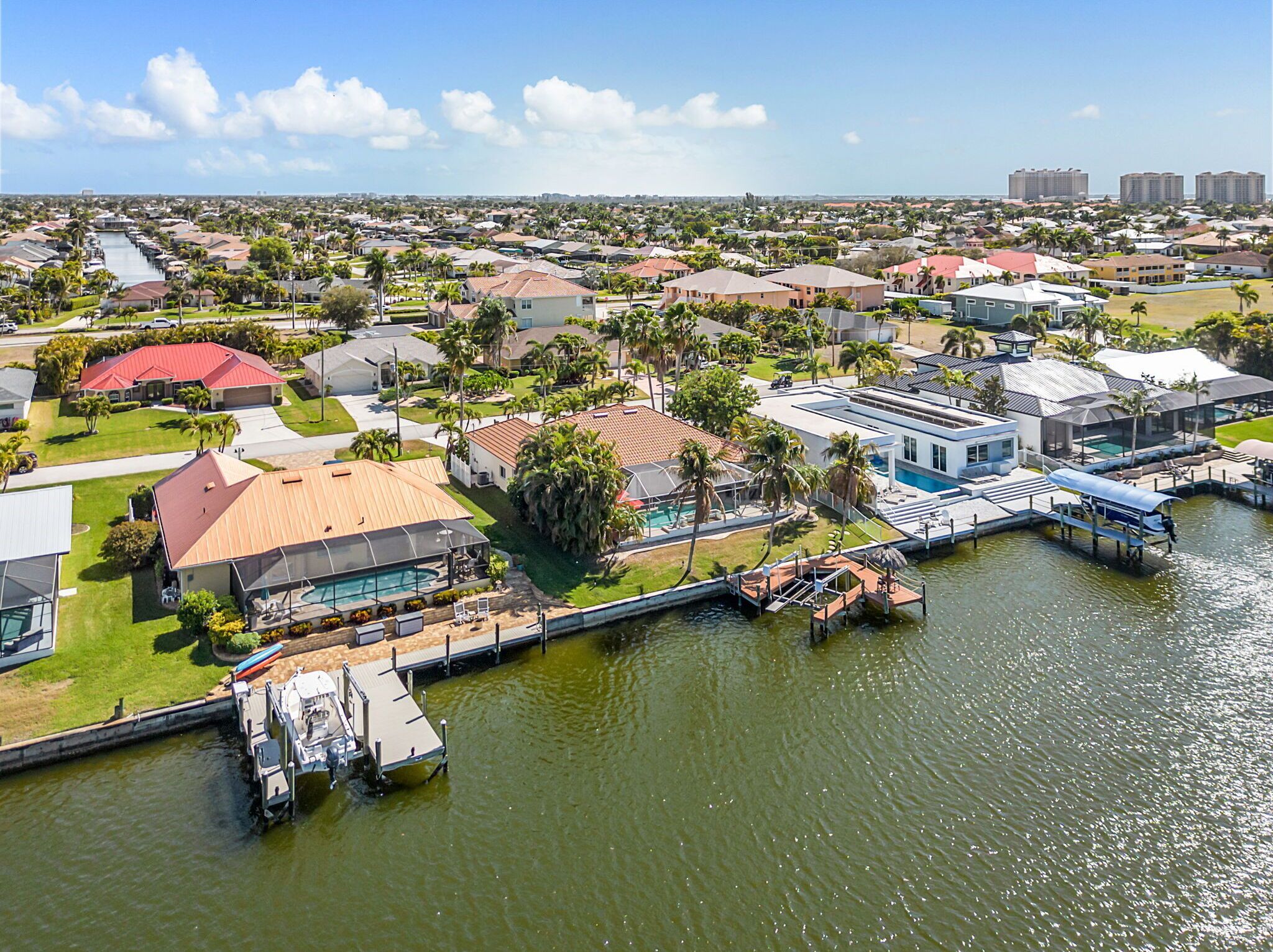 A residential area with houses, a swimming pool, and a dock extending into a body of water.