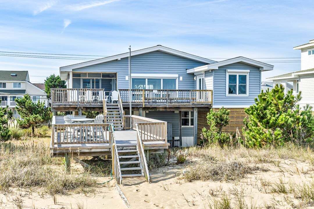 A two-story beach house with a balcony and a deck.
