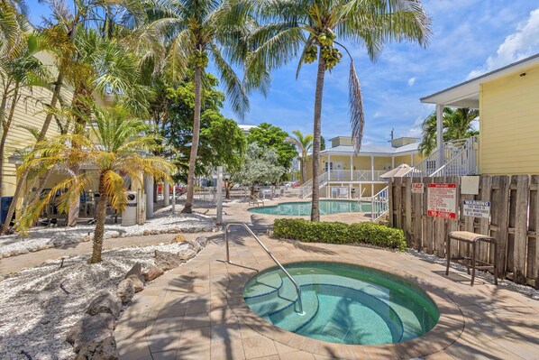 A pool area with palm trees, a small pool, and a wooden fence.