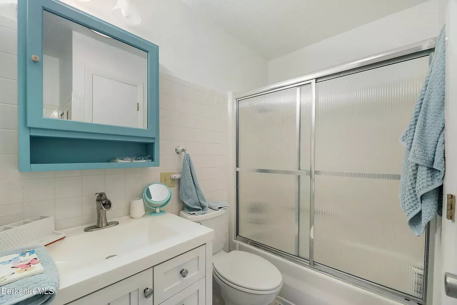 Een badkamer met een wit wastafelmeubel, een spiegel, een toilet en een douchecabine van glas.
