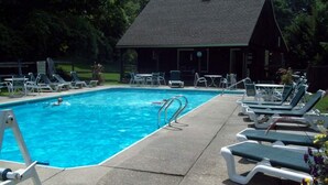 A swimming pool with lounge chairs and a covered area.