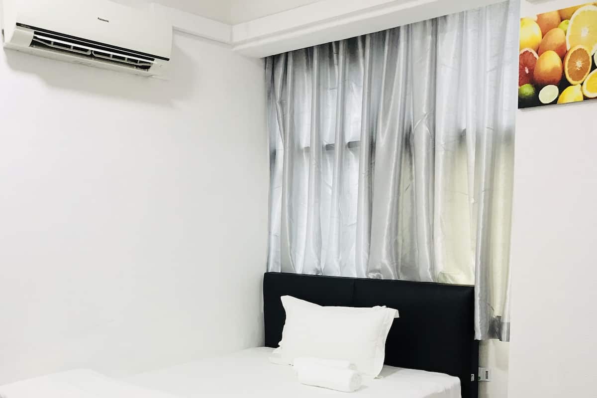 A neatly made bed with white linens in a room with a black headboard.